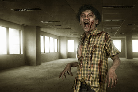 Bloody asian zombie man with mad face in the dark roomの写真素材