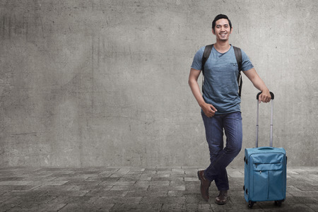 Young asian tourist on vacation with suitcase on the city streetの写真素材