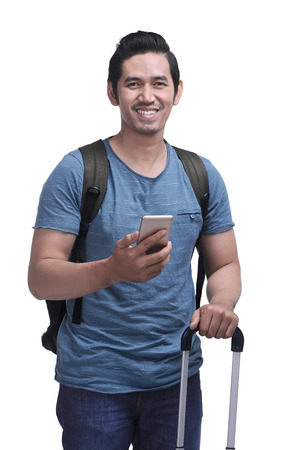 Young asian man tourist holding his smartphone isolated over white backgroundの写真素材