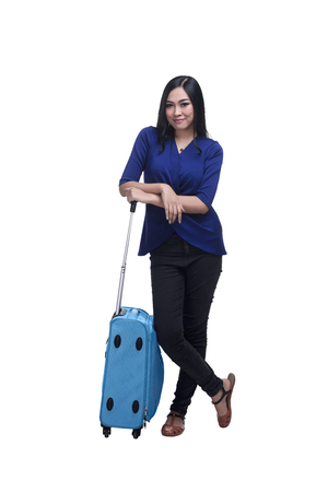 Young asian woman traveler posing beside a suitcase isolated over white backgroundの写真素材