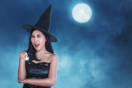 Pretty asian woman with fairy dress holding magic wand at moonlightの写真素材