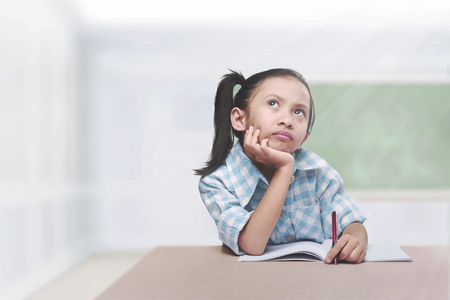 Cute asian child with book and pen learning in the schoolの写真素材