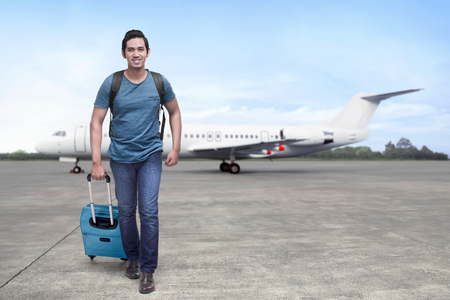 Traveler asian man get off the plane with suitcase in the airportの写真素材
