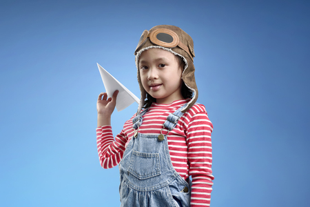 Beautiful asian little girl dreams of becoming a pilot against summer sky backgroundの写真素材