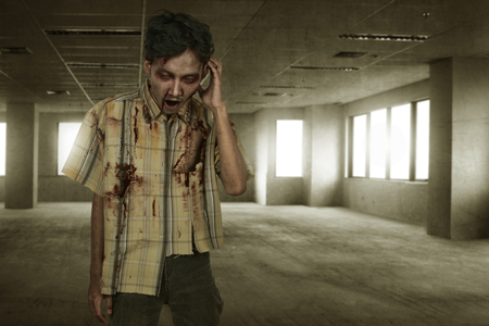 Spooky asian zombie man with wounded face on empty roomの写真素材