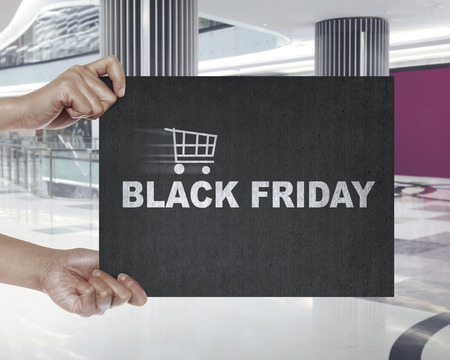 Hand holding signboard with shopping cart and Black Friday text. Black friday conceptの写真素材