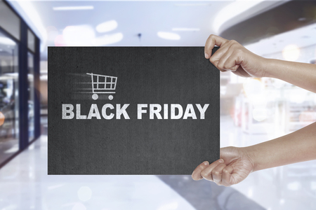 Hand holding signboard with shopping cart and Black Friday text. Black friday conceptの写真素材