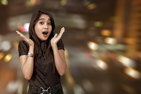 Excited asian woman celebrating Black Friday against blured lights backgroundの写真素材