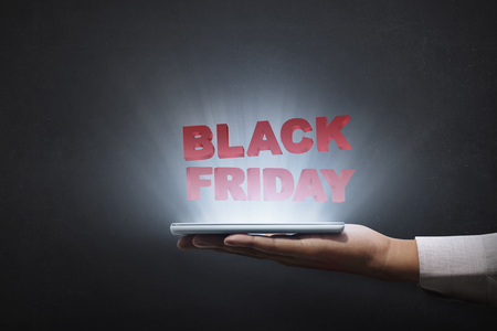 People holding tablet and showing Black Friday advert over black backgroundの写真素材