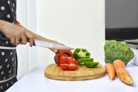 Woman slicing peppers and cooking in the kitchenの写真素材