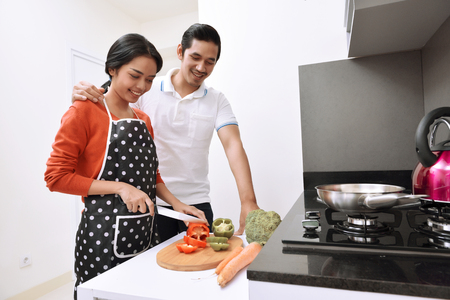 Portrait of asian couple smiling and cooking together in the kitchenの写真素材