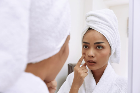 Young asian woman with bath towels cleanses her face at the bathroomの写真素材