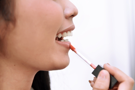Close-up beautiful woman applying red lipstick on her lips when makeupの写真素材