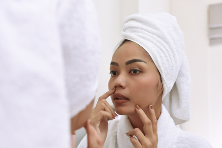 Young asian woman with bath towels cleanses her face at the bathroomの写真素材