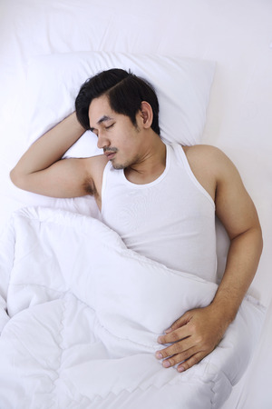 Handsome asian man sleep tightly in his bedroomの写真素材