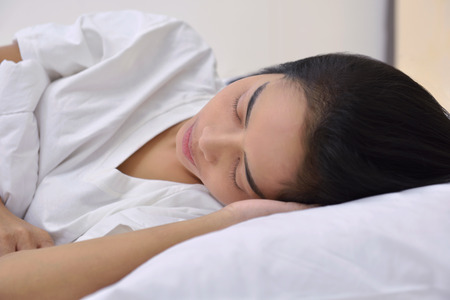 Young asian woman sleeping with head lying on hand in the bedroomの写真素材