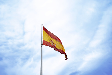 Spain Flag waving over blue sky backgroundの写真素材