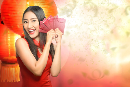 Happy chinese woman in traditional clothing holding red envelope. Happy Chinese New Yearの写真素材