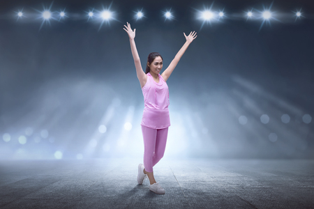 Excited asian runner woman after exercising with spotlight backgroundの写真素材