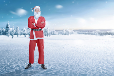 Young asian man with Santa Claus costume standing on winter backgroundの写真素材