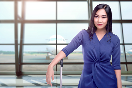 Young asian tourist woman standing with suitcases on the airport terminalの写真素材