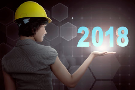 Back view of asian engineer woman with protection helmet showing 2018 numbers. Happy New Year 2018