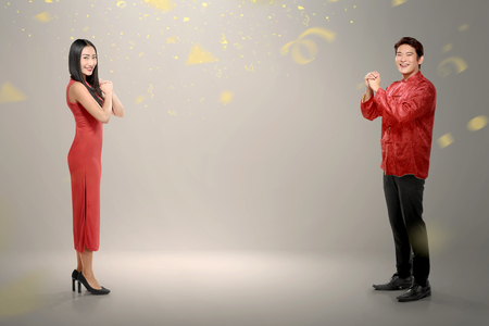 Side view of chinese couple in traditional dress with confetti on grey wall backgroundの写真素材