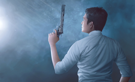Young asian man police with uniform holding guns in his hands over dark backgronudの写真素材