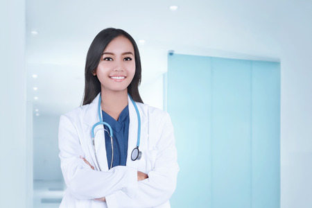 Beautiful asian doctor woman in white coat with crossed hands on clinicの写真素材