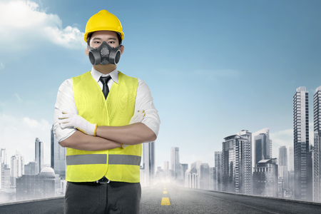 Handsome asian worker in a reflective vest standing on the urban roadの写真素材