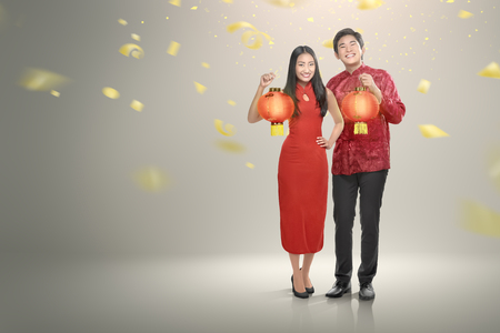 Happy chinese couple in cheongsam clothes holding red lanterns with confetti background. Happy Chinese New Yearの写真素材