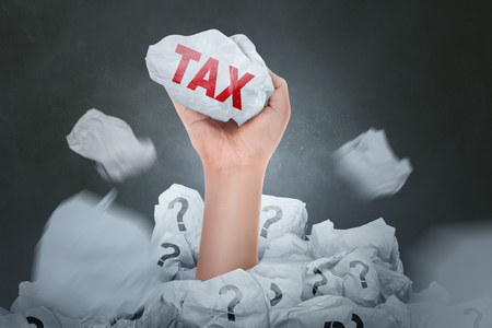 People hand holding paper with Tax sign over dark backgroundの写真素材