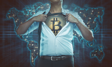 Businessman superhero with bitcoin on his chest over digital world map backgroundの写真素材