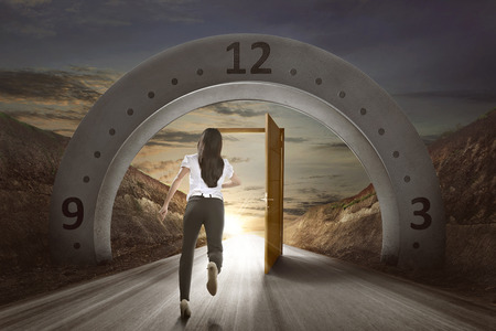 Businesswoman running to open door on the street with gateway arch backgroundの写真素材