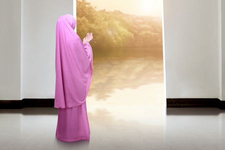 Back view of asian muslim woman praying in the mosque at sunsetの写真素材