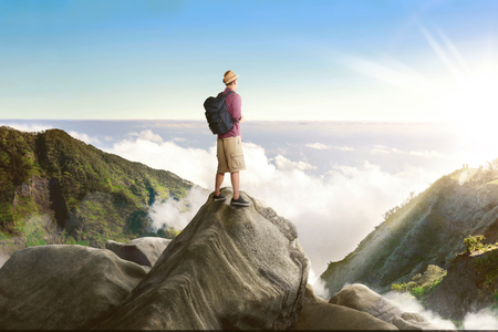 Young asian backpacker standing on the rock looking at landscape viewの写真素材