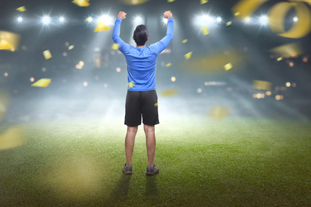 Back view of asian man celebrating his victory with confetti backgroundの写真素材