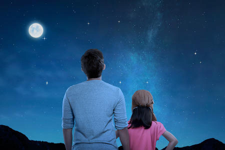 Rear view of father and little daughter looking at night scene at outdoor の写真素材