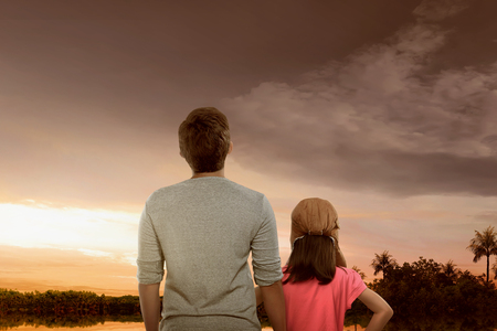 Portrait of father and daughter enjoying sunset view with dramatic sky backgroundの写真素材