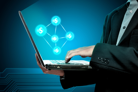 Businessman holding laptop with money network on blue backgroundの写真素材