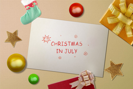 White paper with text Christmas in July with christmas decoration on backgroundの写真素材