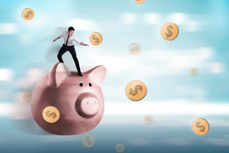 Handsome asian businessman standing on a piggy bank. Summer saving conceptの写真素材