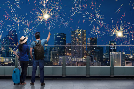 Traveler asian couple standing on terrace and watch the fireworks on the nightの写真素材