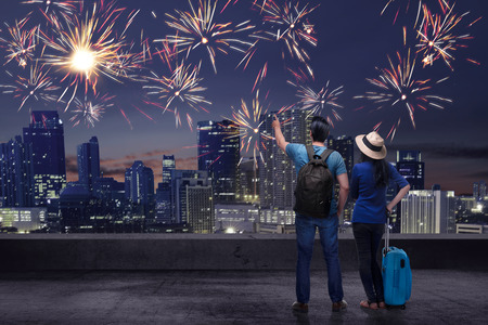 Young asian couple enjoying fireworks on the city at nightの写真素材