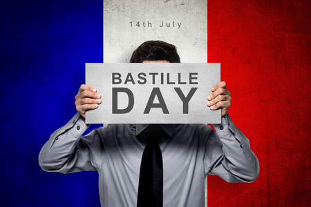 Man holding board with bastille day message over france color flag backgroundの写真素材