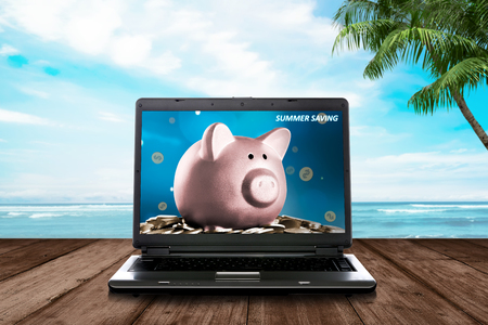 Summer savings sign in laptop at wooden plank. Summer saving conceptの写真素材