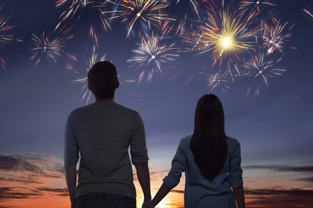Young asian couple watching spectacular fireworks on the skyの写真素材