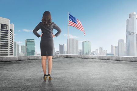 Rear view of businesswoman looking at american flag on top of the roof. Independence day 4th of Julyの写真素材