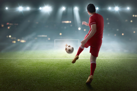 Young asian soccer player shooting the ball on the matchの写真素材