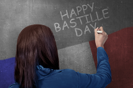 Rear view of woman writing happy bastille day on the wall. Happy Bastille Dayの写真素材
